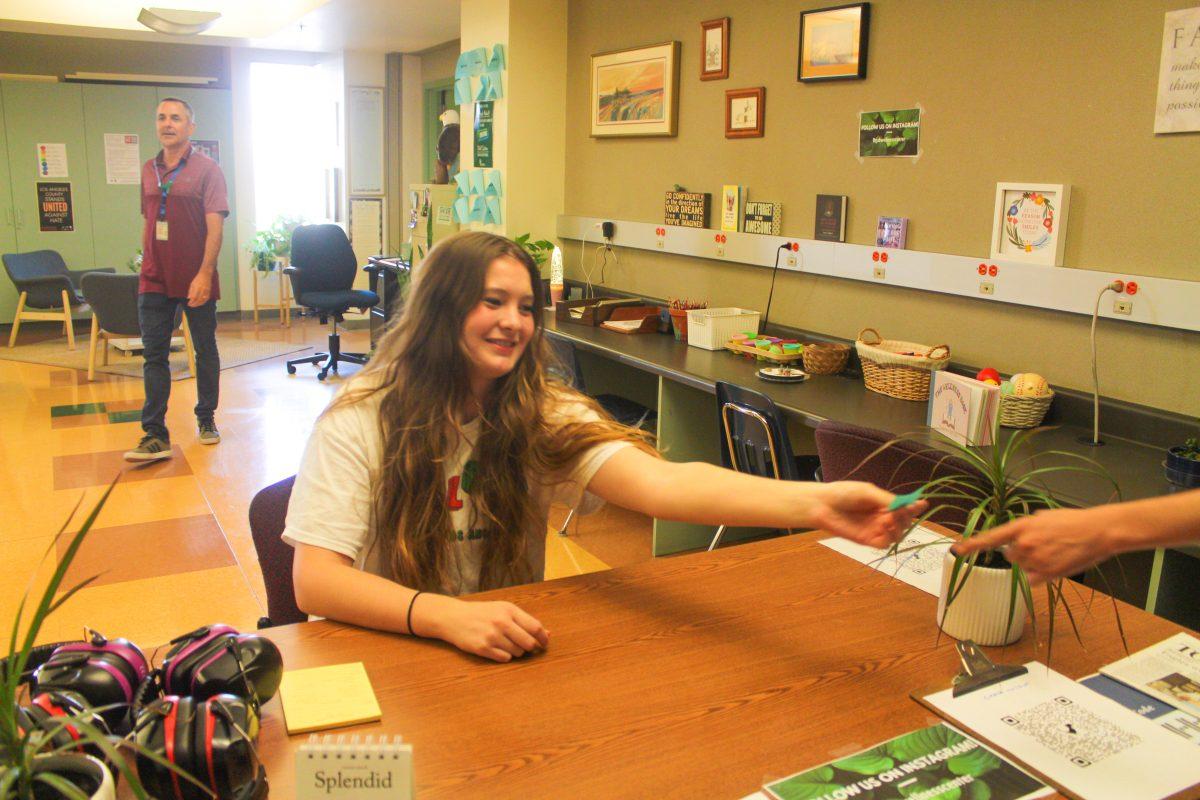 HELPING HAND  Senior Emilia Esseln helps a student check in at the Wellness Center. 
