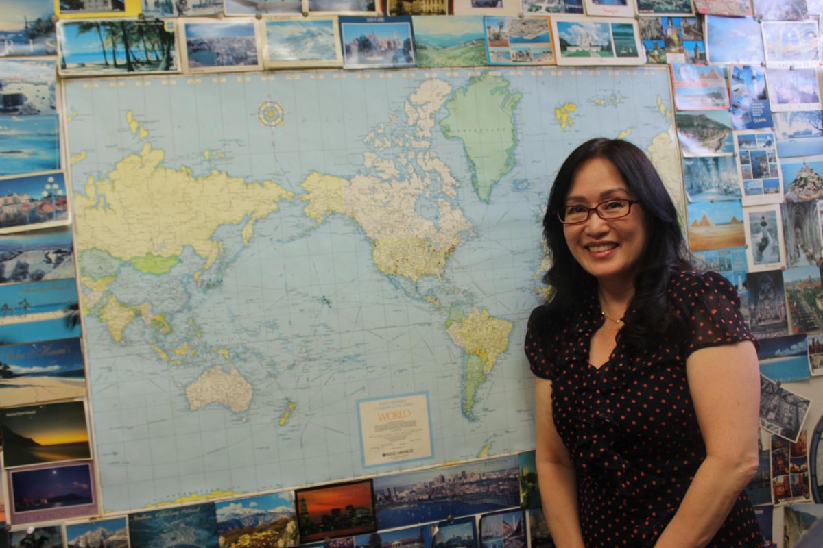 Borja poses in front of the world map in her office, surrounded by a plethora of postcards shes gathered over the years from past and current students. 